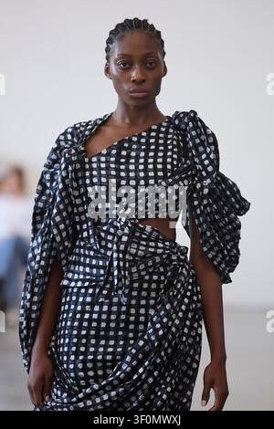 Berlin, Allemagne, 5 juillet 2026. Un mannequin défile pour Fruche dans une robe à carreaux noir et blanc nouée lors de la Berlin Fashion Week SS27. Banque D'Images