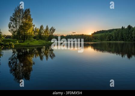 Un lac forestier tranquille en Russie centrale capture un coucher de soleil d'été éclatant. Banque D'Images