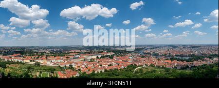 République tchèque, Prague - 25 juin 2026 : Vue montrant la ville de Prague avec des toits, des arbres, une rivière et des nuages dans le ciel Banque D'Images