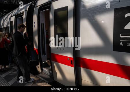 Les passagers se tiennent debout et montent par les portes ouvertes d'un train Deutsche Bahn DB sur un quai de la gare centrale de Cologne à Cologne, en Rhénanie-du-Nord-Westphalie, en Allemagne en juin Banque D'Images