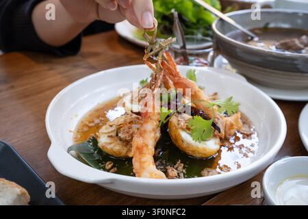 Œufs de gendre thaïlandais avec crevettes frites dans une sauce au tamarin, garnis d'échalotes frites et de coriandre sur une assiette blanche Banque D'Images