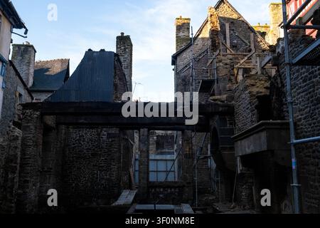 Vue extérieure du site de reconstruction de la Maison de la Mere Pourcel avec des murs en pierre, du bois carbonisé, des échafaudages et une couverture de toit temporaire en hauteur Banque D'Images