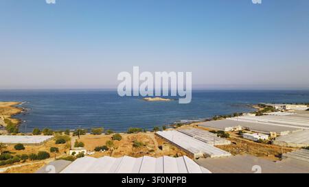 Serres s'étendant à travers les terres près de la côte, rencontrant la mer et le ciel bleu clair sous la lumière du soleil Banque D'Images