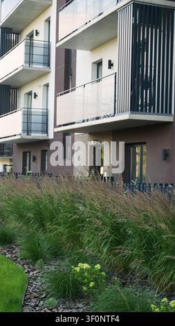 Bâtiment résidentiel moderne doté de balcons et d'un jardin urbain magnifiquement aménagé avec de hautes herbes Banque D'Images