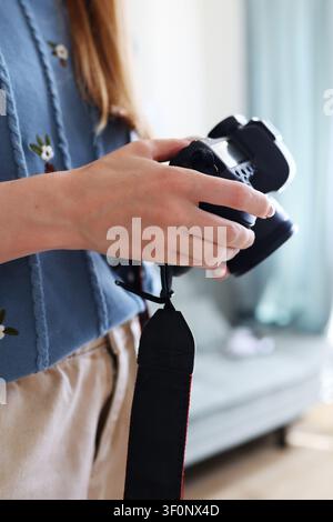 Gros plan d'une femme tenant un appareil photo sans miroir et ajustant les paramètres, équipement photographique et concept de style de vie créatif. Banque D'Images