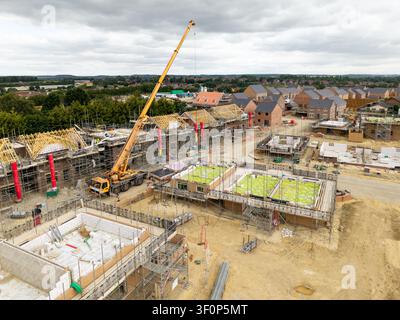 Vue aérienne du paysage au-dessus d'un chantier de construction de maisons neuves et abordables écologiques pour combler le manque de logements au Royaume-Uni sur la ceinture verte Banque D'Images