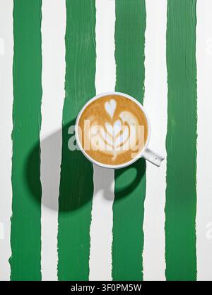 tasse à cappuccino en céramique blanche sur une table rayée vert et blanc peinte, vue de dessus Banque D'Images