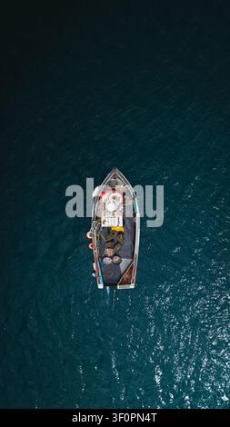 Vue aérienne directement au-dessus d'un petit bateau de pêche traditionnel cornique et d'un pêcheur en eau libre pêchant des crabes, des homards et une augmentation des pieuvres Banque D'Images