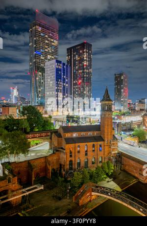 Centre-ville de Manchester illuminé la nuit vu du ciel, mettant en valeur la ligne d'horizon, le quartier commercial et les sites emblématiques du Grand Manchester. Banque D'Images