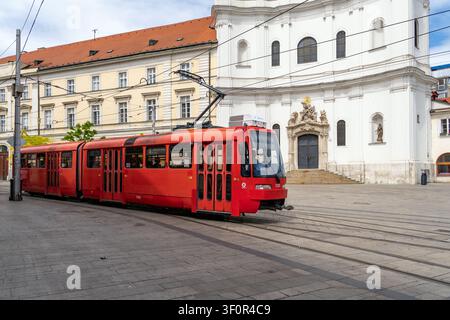 Tramway rouge passant devant l'église trinitaine au centre-ville de Bratislava, Slovaquie Banque D'Images