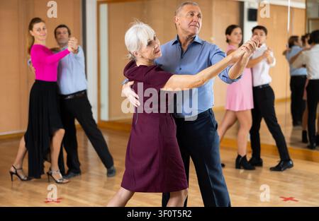 Couple de personnes âgées gaies pratiquant des danses de salle de bal dans la salle de bal Banque D'Images