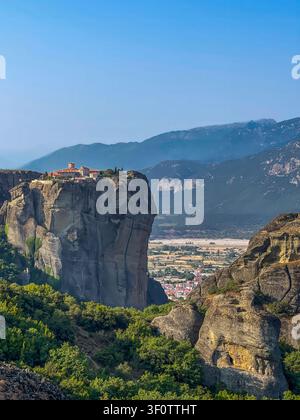 Kalambaka, Grèce – 24 juillet 2024 : groupe de monastères de Meteora. Monastère de la Sainte-Trinité sur son plateau rocheux, avec, bien en contrebas, la ville de Kalambaka Banque D'Images