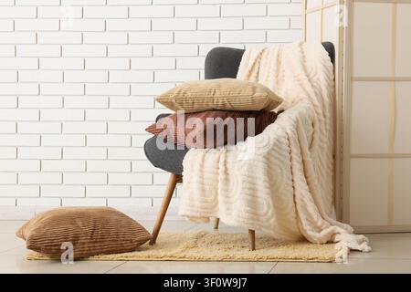 Fauteuil confortable avec des coussins en velours empilés et une couverture douce dans un intérieur moderne de salon Banque D'Images
