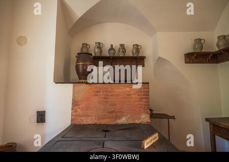 Intérieur de cuisine de château médiéval avec plaque de cuisson en fer ancien, pots en argile sur des étagères en bois et détail de mur en briques à Stolzenfels, Allemagne Banque D'Images