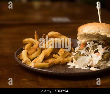 Burger gourmet au bœuf servi avec des frites croustillantes Banque D'Images
