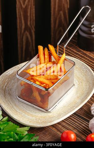 Frites de patate douce dans un panier à friture miniature sur une assiette Banque D'Images