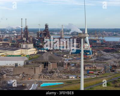 Velsen-Noord, Pays-Bas – 06 juillet 2026 : Vue aérienne de l’usine Tata Steel avec des structures industrielles, des cheminées et une éolienne au premier plan Banque D'Images