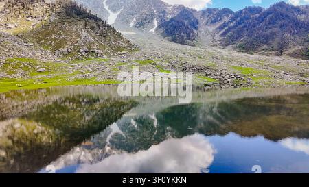 Une vue panoramique à angle élevé du lac Kareri reflétant les montagnes accidentées de l'Himalaya et le ciel bleu au Himachal Pradesh. Banque D'Images