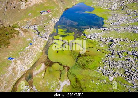 Une perspective aérienne par drone du lac Kareri immaculé entouré de paysages montagneux rocheux dans l'Himachal Pradesh. Banque D'Images