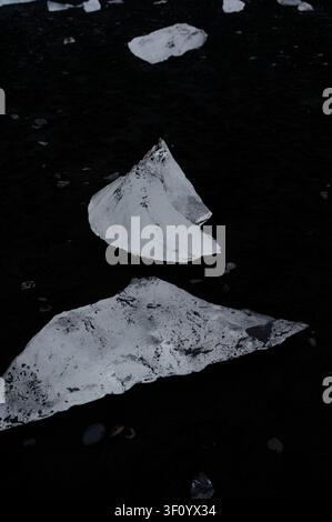 Des morceaux de glace glaciaire reposent sur le sable volcanique noir de Diamond Beach comme des fragments épars d'un glacier brisé. Banque D'Images
