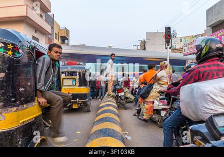 Trafic intense avec des auto-rickshaws, des motos et des piétons attendant à un passage à niveau à Bikaner, Rajasthan, Inde. Banque D'Images