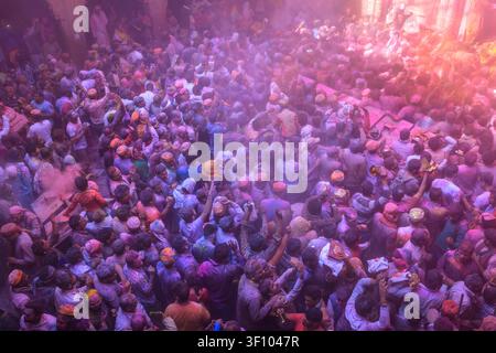Vue en contre-plongée de foules massives de dévots célébrant le festival coloré Holi avec de la poudre gulal magenta à l'intérieur d'un temple historique à Vrindavan Banque D'Images