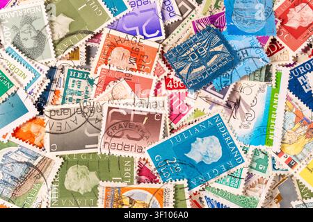 De nombreuses timbres postaux sont étalés sur une table. Ils viennent de différentes nations et présentent divers designs et couleurs. Les timbres montrent leur f unique Banque D'Images