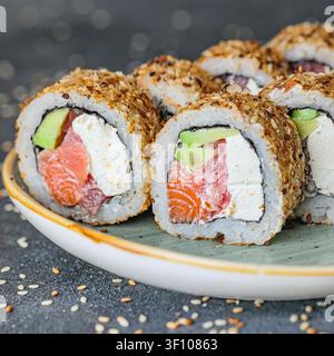 Une assiette remplie de sushi frais, comprenant divers types de rolls, sashimi et nigiri, posée sur une table. Banque D'Images