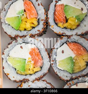 Une boîte remplie de plusieurs rouleaux de sushi présentant une variété de garnitures disposées de manière attrayante. Banque D'Images