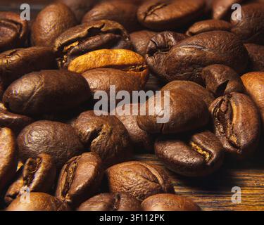 Macro rapproché de grains de café torréfiés sombres empilés, avec un seul grain plus clair, doré-brûlé, se distinguant parmi les grains plus sombres, montrant la richesse Banque D'Images