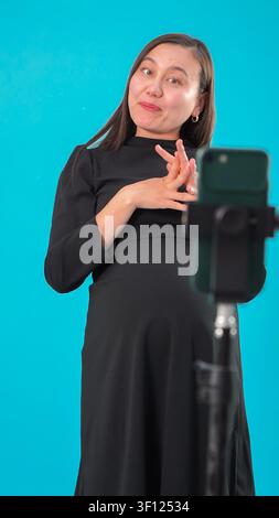 Femme enceinte gesticulant en enregistrant une vidéo sur un smartphone Banque D'Images