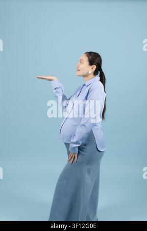 Jeune femme souriante présentant quelque chose avec un geste de la main ouvert Banque D'Images