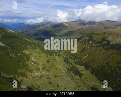 Paysage montagneux verdoyant étendu avec des vallées sous un ciel nuageux dramatique, vue aérienne, près de Ranca, Route haute Transalpina, Drum national 67C, nati Banque D'Images
