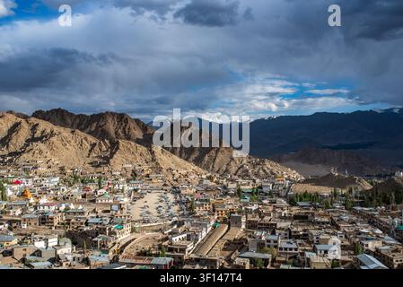 Une vue impressionnante en contre-plongée révèle la ville de Leh nichée dans la vallée, dominée par des collines arides imposantes et entourée en arrière-plan par de hauts Banque D'Images