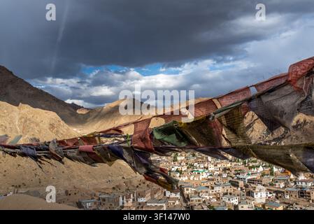 Des drapeaux de prière tibétains effilochés et colorés flottent au premier plan, ouvrant sur une vue panoramique large en hauteur sur la ville de Leh et le majestueux Barr Banque D'Images