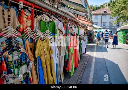 Visiteurs passant devant des étals de vêtements colorés au Marché Central de Ljubljana à Ljubljana, en Slovénie. Banque D'Images