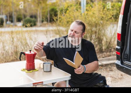 Homme avec une jambe prothétique profitant d'un café en camping Banque D'Images