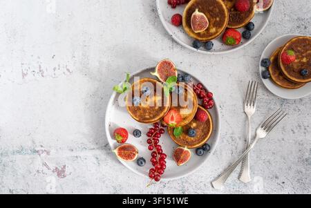 Composition de petit-déjeuner en hauteur mettant en vedette des gaufres à pancake garnies de baies fraîches et de fruits de saison Banque D'Images