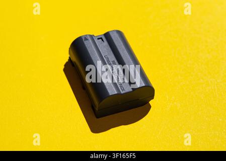 Prise de studio d'une batterie d'alimentation noire rechargeable pour appareil photo isolée sur un fond jaune vif, représentant une énergie portable, un équipement photographique, un Banque D'Images