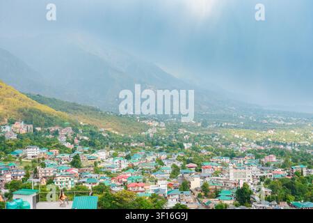 Une vue grand angle de la ville de Dharamshala nichée dans les montagnes luxuriantes et vertes de l'Himalaya sous un ciel nuageux et brumeux. Banque D'Images