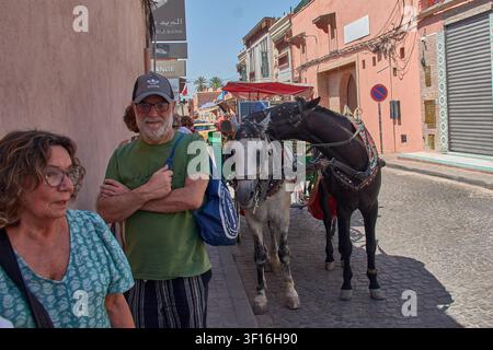 Marrakech, Maroc, 2 juin 2026, un couple de touristes adultes pose calmement sur une rue pavée dans la médina de Marrakech, Maroc, avec deux chevaux p Banque D'Images