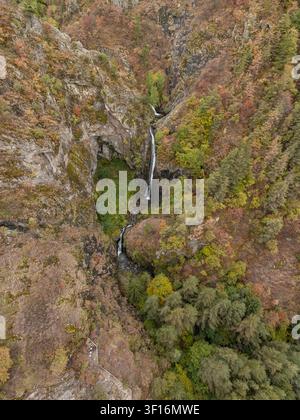 Vue aérienne de la cascade Ovcharenski Goritsa dévalant des falaises rocheuses entourées d'une forêt automnale vibrante et d'une forêt dense à Ovchartsi, Kyus Banque D'Images