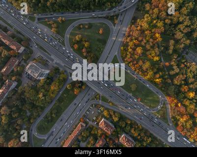 Vue aérienne d'une interchange autoroutière entourée d'arbres d'automne vibrants et de bâtiments urbains à Sofia, province de la ville de Sofia, Bulgarie. Banque D'Images