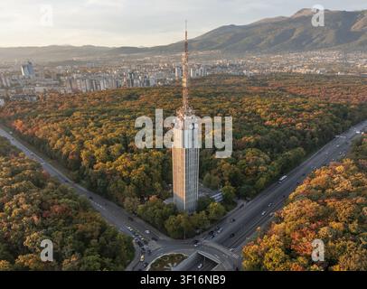 Vue aérienne de la tour télévisée de Sofia entourée d'une forêt automnale vibrante, avec la ligne d'horizon de la ville et la montagne Vitosha en arrière-plan Sofia, province de la ville de Sofia Banque D'Images