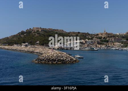 Brise-lames en pierre avec phare à l'entrée du port de Mgarr sur l'île de Gozo, Malte, le 19 juin 2026. Banque D'Images
