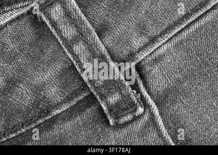 Vue en monochromie par le dessus d'une boucle de ceinture en tissu denim montrant des points de couture détaillés en tissage de coton. Composition minimaliste en flat lay avec des tons neutres. Idéale pour f Banque D'Images