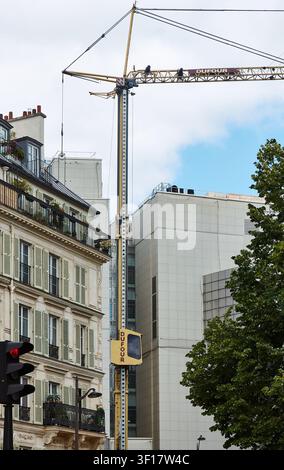 Paris, France – 11 mai 2026 : Grue de construction Dufour positionnée entre des bâtiments modernes et traditionnels à Paris, mettant en évidence le développement urbain a Banque D'Images