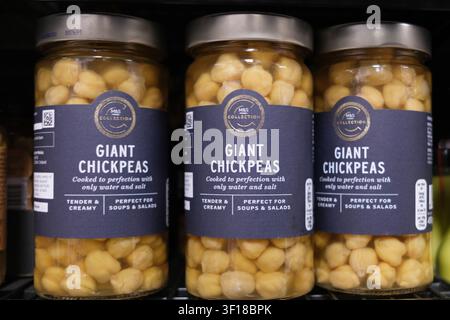 Epsom, Londres UK, 11 juillet 2026, Une mise en gros de bocaux en verre contenant des pois chiches géants premium cuits sur une étagère de supermarché sans personnes Banque D'Images