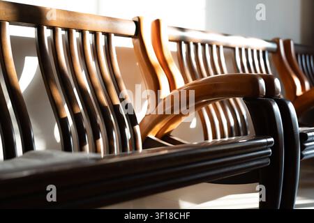 Bancs en bois traditionnels avec lattes et accoudoirs courbés dans un espace intérieur baigné de lumière, peut-être un Banque D'Images