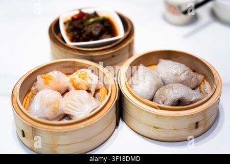 Dim sum de style Hong Kong servi dans des vapeurs traditionnels en bambou – boulettes de crevettes, petits pains au porc et Banque D'Images